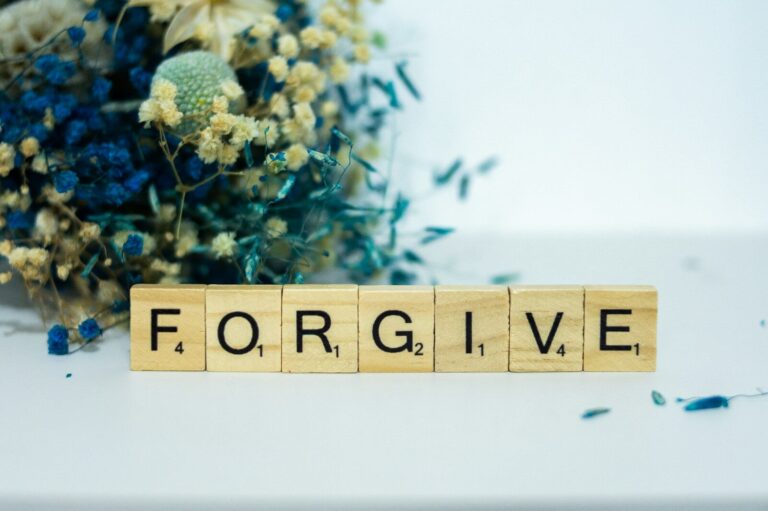 a wooden block that says forgive next to a bouquet of flowers