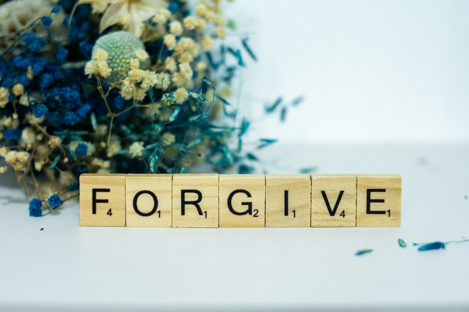a wooden block that says forgive next to a bouquet of flowers